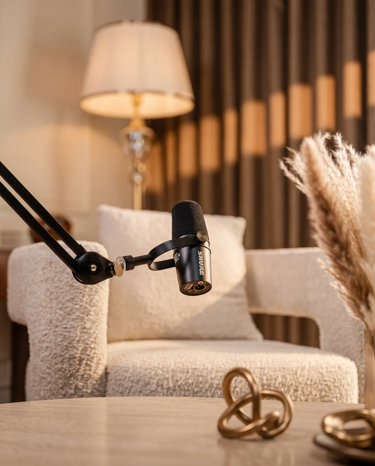 Close-up of a Shure broadcast microphone on a boom arm above the studio table — Podflix Studio Dubai