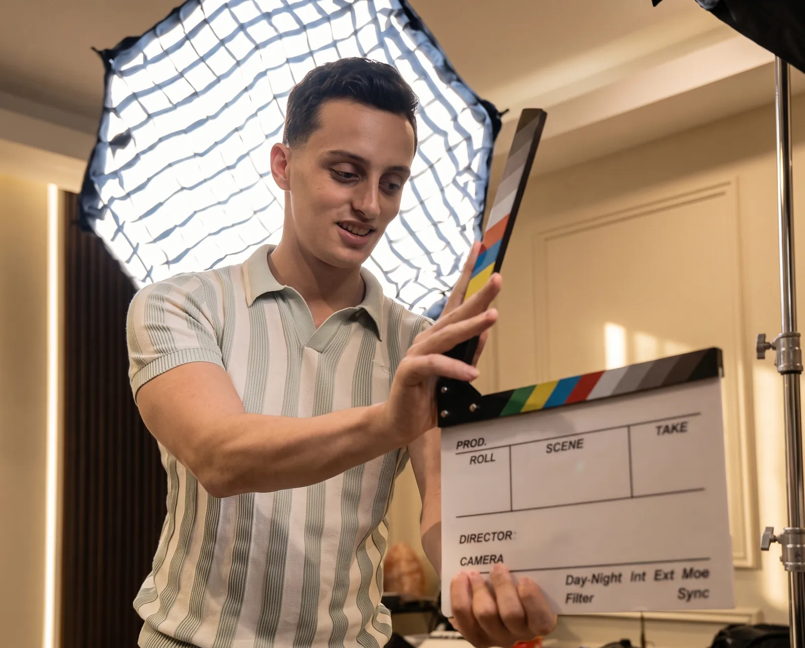 A Podflix crew member marking a take with a clapperboard beside a softbox — Podflix Studio Dubai